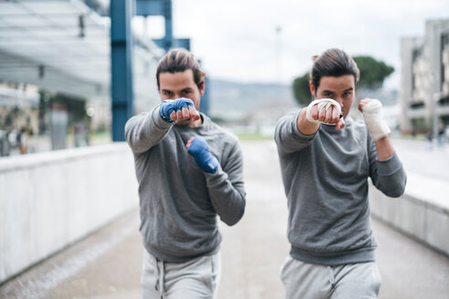 Eineiige männliche erwachsene Zwillingsboxer trainieren im Freien, Kampfhaltung Porträt - CUF46181