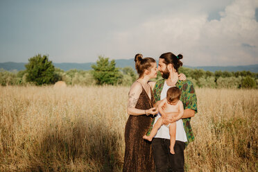 Paar mit kleinem Mädchen auf einer goldenen Grasfläche, Arezzo, Toskana, Italien - CUF46209