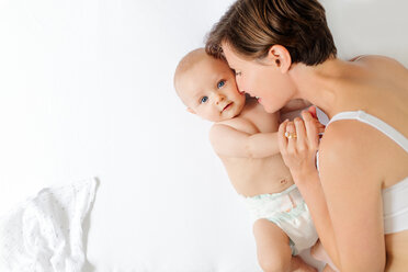 Overhead view of mother and baby boy lying down on white background - CUF46227