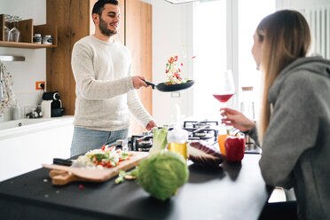 Paar kocht Essen, schwenkt Gemüse in der Pfanne - CUF46250