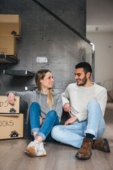 Couple sitting with cardboard boxes, moving home - CUF46251