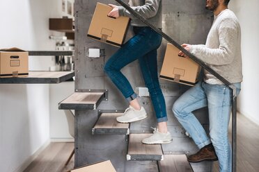 Couple carrying cardboard boxes up stairs - CUF46252