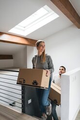 Couple carrying cardboard boxes upstairs - CUF46255