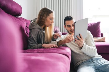Ehepaar entspannt sich auf dem Sofa und benutzt ein digitales Tablet - CUF46259