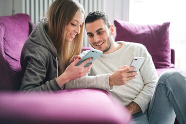 Couple relaxing on sofa using smartphones - CUF46260