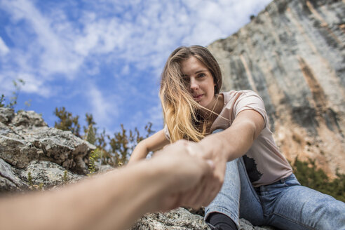 Spain, Alquezar, young woman on a hiking trip giving a helping hand - AFVF01779