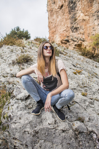 Junge Frau bei einer Wanderung auf einem Felsen sitzend, lizenzfreies Stockfoto