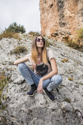 Junge Frau bei einer Wanderung auf einem Felsen sitzend - AFVF01781
