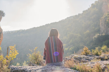 Spain, Alquezar, rear view of young woman on a hiking trip sitting on a rock - AFVF01788