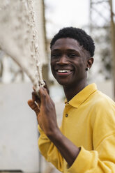 Porträt eines jungen schwarzen Mannes, der am Volleyballnetz steht und lacht - AFVF01797