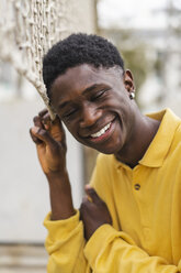 Portrait of a young black man standing by volleyball net, laughing - AFVF01798