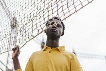 Porträt eines jungen schwarzen Mannes, der am Volleyballnetz steht - AFVF01800