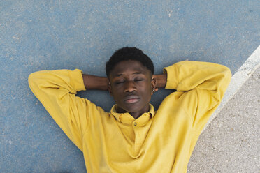 Junger schwarzer Mann, der auf dem Boden schläft, mit den Händen hinter dem Kopf - AFVF01802