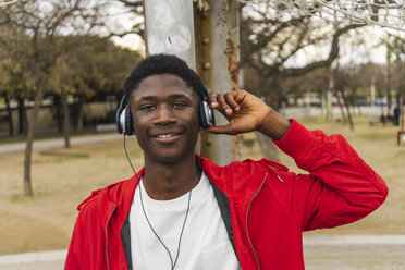 Junger schwarzer Mann mit Kopfhörern, lächelnd, Porträt - AFVF01804