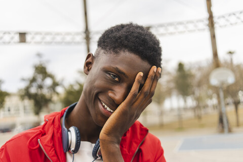 Porträt eines jungen schwarzen Mannes, lachend mit der Hand im Gesicht, lizenzfreies Stockfoto