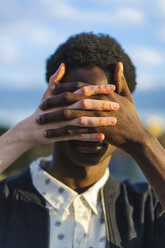 Hands covering eyes of a young black man - AFVF01831