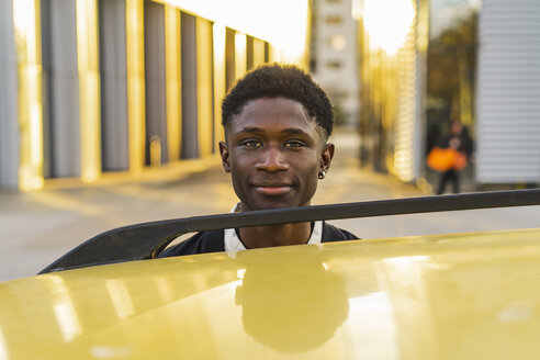 Porträt eines schwarzen jungen Mannes, der neben einem Auto steht - AFVF01832