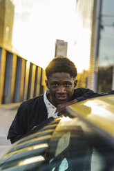 Porträt eines schwarzen jungen Mannes, der neben einem Auto steht - AFVF01833