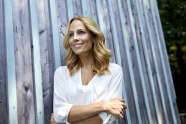 Smiling blond woman in front of wooden wall - PNEF01020