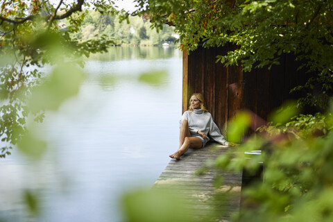 Relaxed woman sitting on wooden jetty at a remote lake stock photo