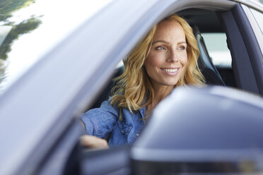 Lächelnde Frau, die Auto fährt und aus dem Fenster schaut - PNEF01058