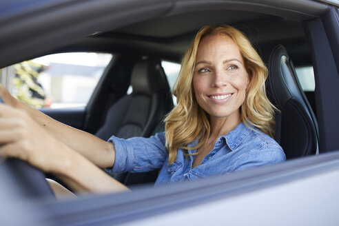 Lächelnde Frau, die Auto fährt und aus dem Fenster schaut - PNEF01063