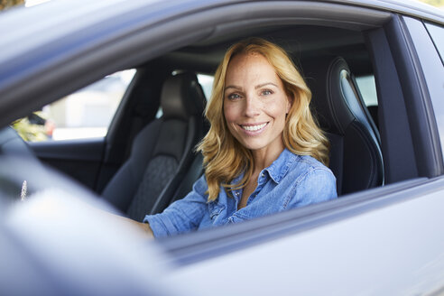 Porträt einer lächelnden Frau, die Auto fährt und aus dem Fenster schaut - PNEF01064