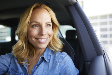Portrait of smiling woman driving car looking out of window - PNEF01065