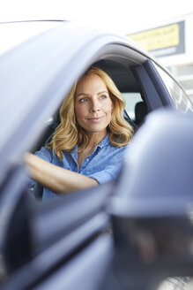 Smiling woman driving car looking out of window - PNEF01067