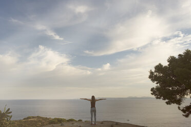 Spain, Catalonia, Barcelona, woman standing with raised arms on viewpoint, Cap de Creus Natural Park - SKCF00533