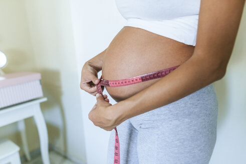 Nahaufnahme einer schwangeren Frau, die ihren Bauch misst - KIJF02045