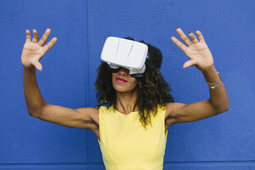 Frau mit Virtual-Reality-Brille vor blauem Hintergrund - FMGF00075