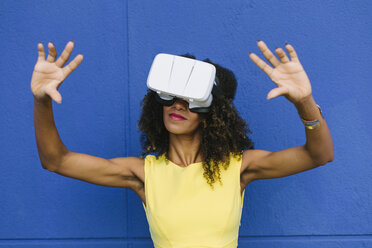 Woman using Virtual Reality Glasses against blue background - FMGF00075