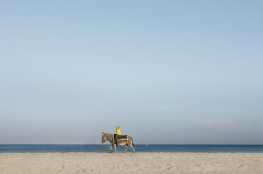 Mädchen reitet auf Esel am Strand, Wiendorf, Mecklenburg-Vorpommern, Deutschland - FSIF03318