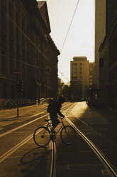 Radfahrender Pendler auf einer sonnigen Straße, Berlin, Deutschland - FSIF03344