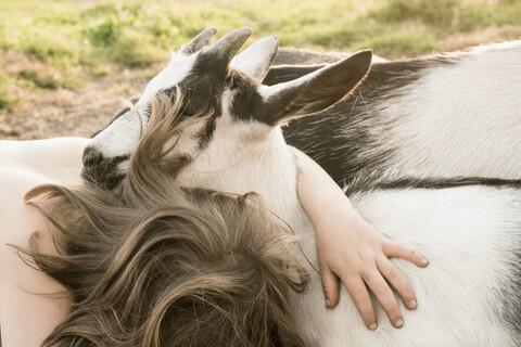 Mädchen umarmt Ziege, lizenzfreies Stockfoto