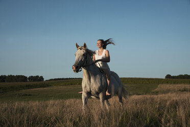 Mädchen reitet auf einem Pferd in einem sonnigen, ländlichen Feld - FSIF03391