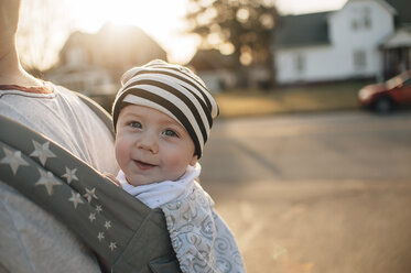 Mittelteil eines Vaters, der seine Tochter in einer Babytrage trägt, während er bei Sonnenuntergang auf der Straße steht - CAVF49124