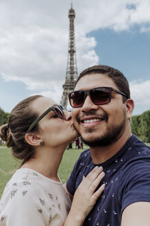 Porträt einer liebenden Freundin, die ihren lächelnden Freund vor dem Eiffelturm in der Stadt küsst - CAVF49133