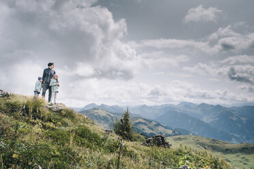 Mother with daughters standing on mountain against cloudy sky - CAVF49138