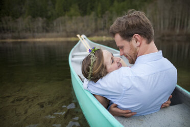 Junges Paar, das sich beim Entspannen im Kanu auf einem See von Angesicht zu Angesicht sieht - CAVF49150