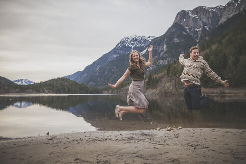 Ganzkörperporträt eines verspielten jungen Paares, das am Seeufer des Silver Lake Provincial Park springt - CAVF49156