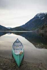 Canoe moored on lakeshore at Silver Lake Provincial Park against mountains during sunset - CAVF49158