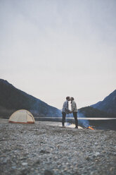 Side view of couple kissing while standing on lakeshore against clear sky during sunset at Silver Lake Provincial Park - CAVF49162