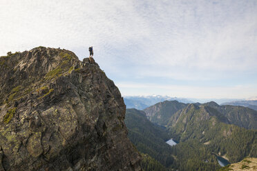 Blick aus der mittleren Entfernung auf einen Wanderer, der auf einer Klippe gegen den Himmel steht - CAVF49165