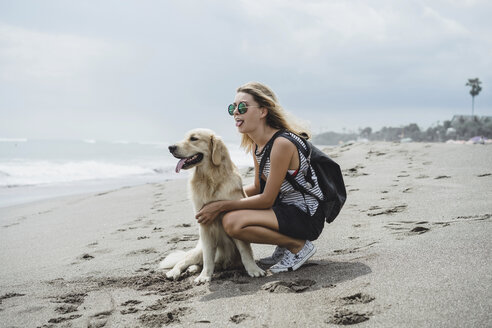 Frau und Labrador Retriever in voller Länge, die ihre Zungen am Strand herausstrecken - CAVF49236