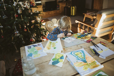 Hochformatige Ansicht eines Mädchens, das zu Hause während der Weihnachtszeit auf Papier malt - CAVF49249