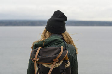 Rear view of woman with backpack standing by sea against cloudy sky at Discovery Park - CAVF49273