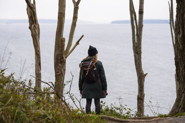 Rear view of woman with backpack standing by sea against sky at Discovery Park - CAVF49274