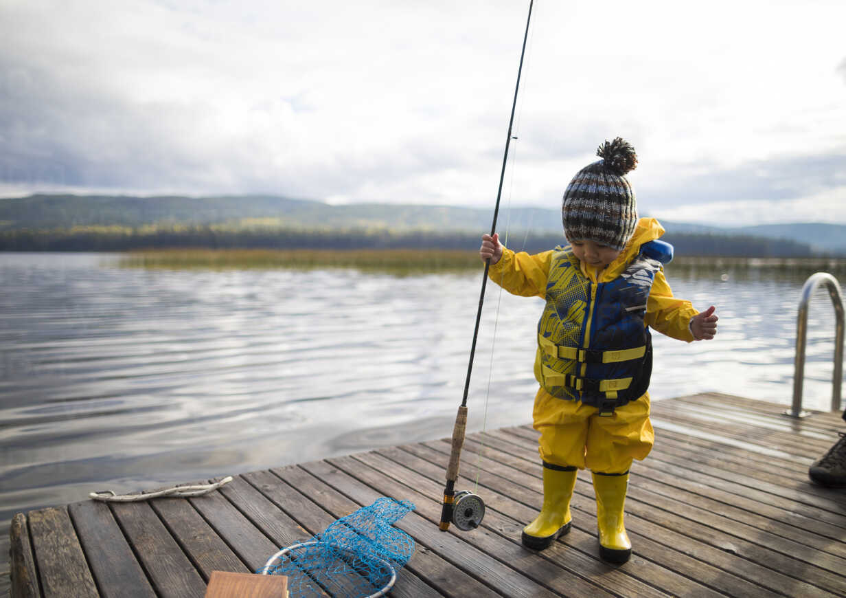 Cute Little Child Girl in Rubber Boots Fishing from Wooden Pier on
